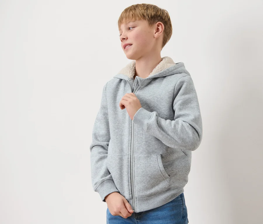 Junge schließt eine graue Kinder-Sweat-Jacke mit Kapuze und Plüschfutter.