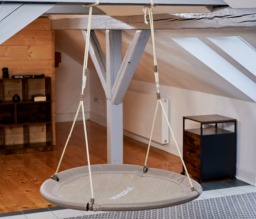 Eine beige HUDORA Nestschaukel »Lounge«, Ø 110 cm hängt von der Decke in einem Innenraum.