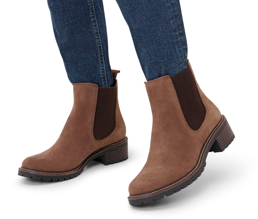 Beine in Jeans, die Veloursleder-Boots tragen.