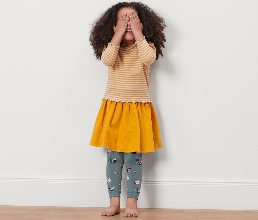 Mädchen hält sich die Augen zu und trägt 2 Kinder-Thermoleggings, Huhn.