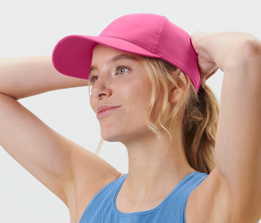 Blonde Frau richtet ihre pinke Sport-Kappe.