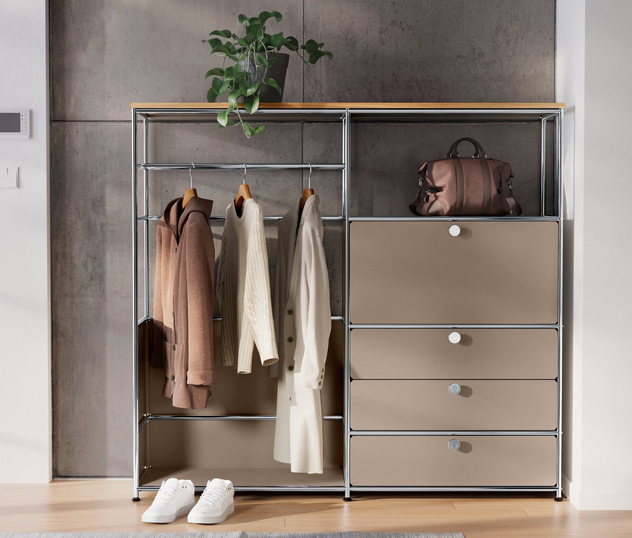 Taupefarbene Kommode Metall »CN3« mit Holzplatte, Kleiderstange, Klappenfach und 3 Schubladen. Auf der Kommode stehen eine Pflanze und eine braune Tasche.