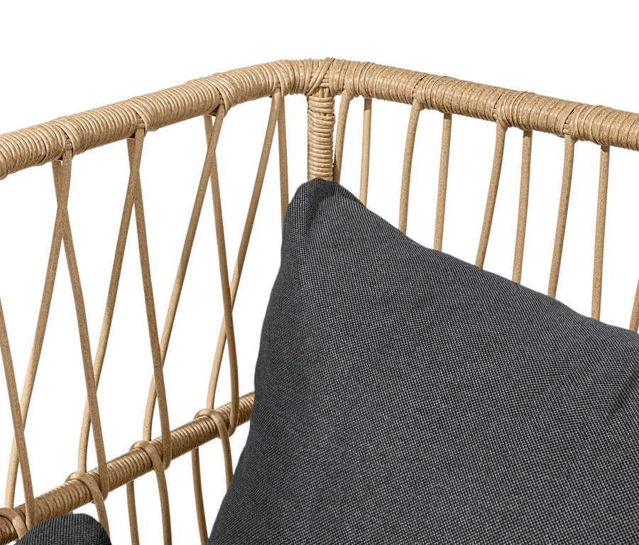 Detailaufnahme eines Loungesofas mit Fußhocker, mit braunem Rattangestell und grauem Kissen.