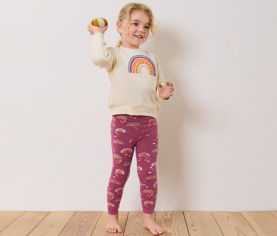 Mädchen wirft Ball, trägt 2 Kinder-Thermoleggings, beere.