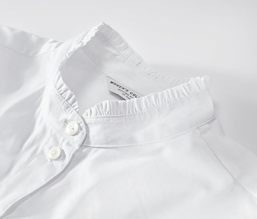 Detailansicht einer weißen Bluse mit Rüschendetail.