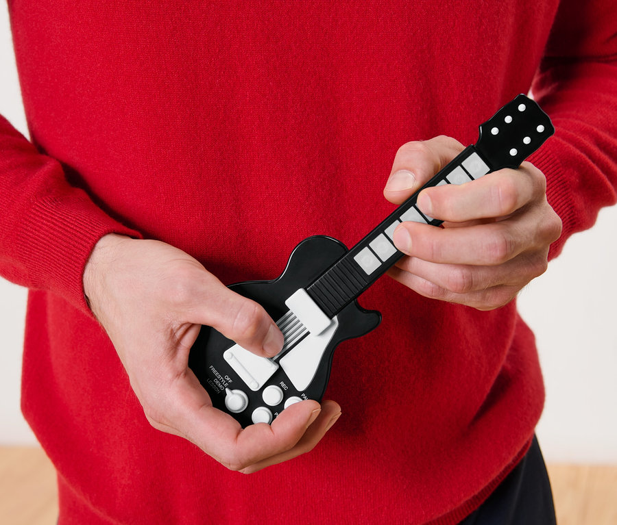 Mann im roten Pullover spielt eine Fingergitarre.