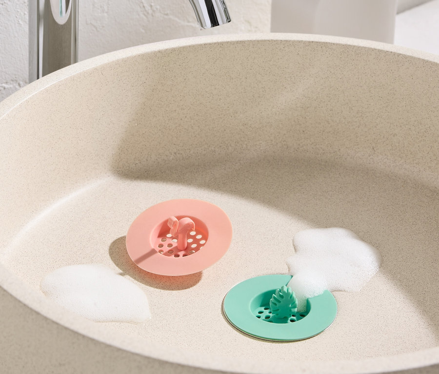 Waschbecken mit rosa und grünem 2 Abflusssiebe aus Silikon und Schaum.