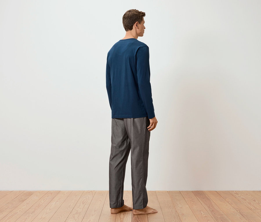Mann von hinten in blauem Pyjama-Oberteil und gewebter Pyjamahose.