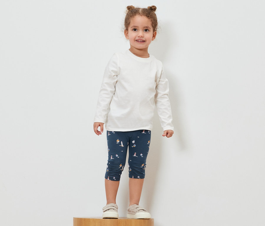 Mädchen steht auf einem Holzsockel und trägt eine maritime 3/4-Leggings.