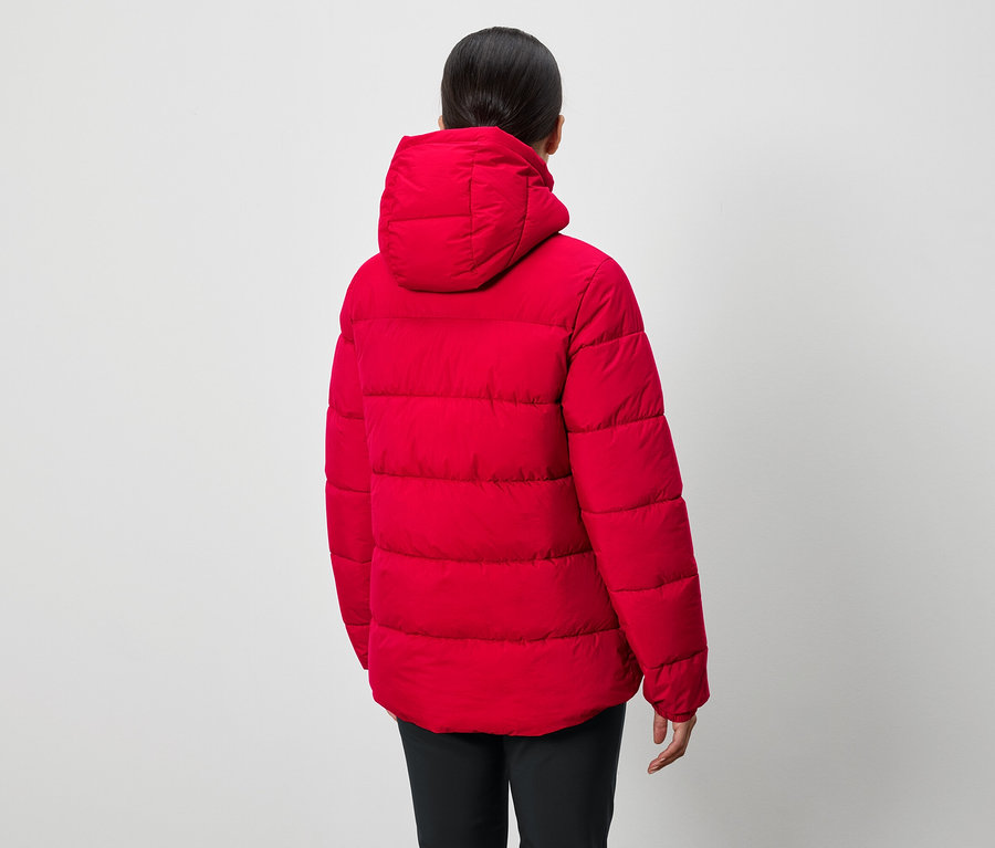 Eine Person mit dem Rücken zur Kamera trägt eine rote Daunenjacke mit Kapuze und eine schwarze Hose.