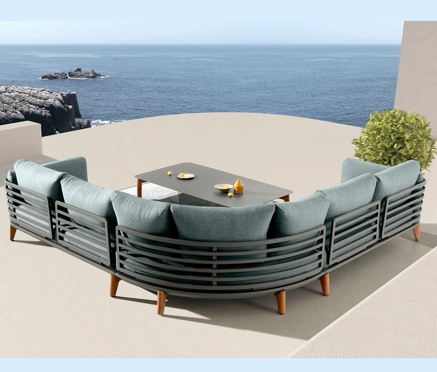 Ansicht der Leco Lounge-Ecke inkl. Tisch »Moss« mit türkisfarbenen Kissen und grauem Rahmen auf einer Terrasse mit Meerblick.