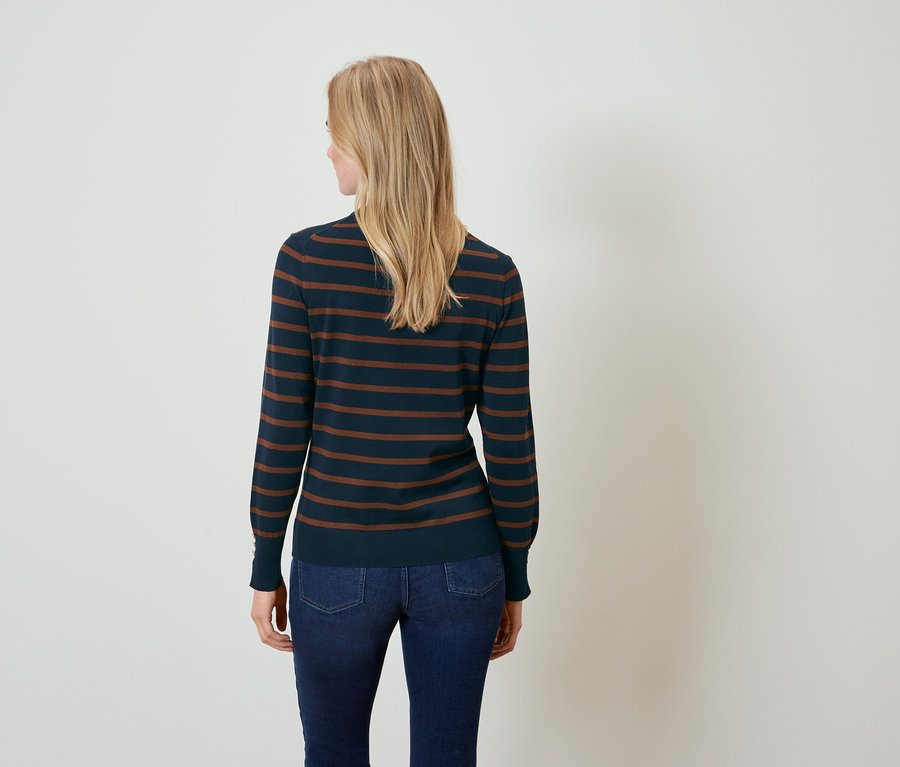 Frau von hinten trägt einen dunkelblauen Pullover mit braunen Streifen und Jeans.