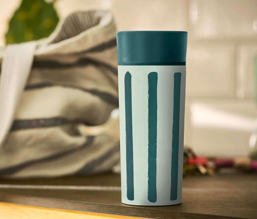 Ein Coffee-to-go-Becher mit Streifen steht auf einem Tisch.