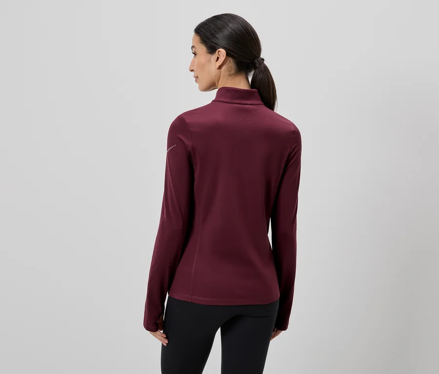 Rückansicht einer Frau mit Pferdeschwanz, die ein langärmliges, weinrotes Oberteil und eine schwarze Hose trägt.