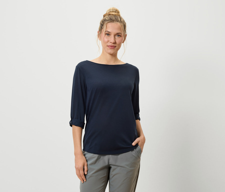 Frau mit Dutt trägt ein marineblaues Shirt und graue Hosen.
