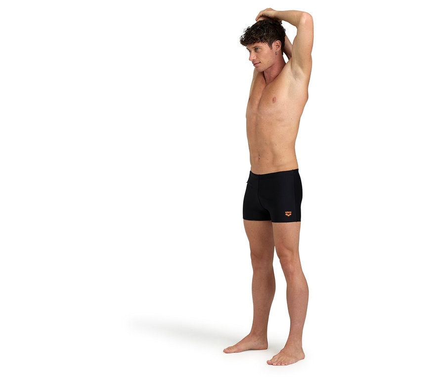 Mann dehnt sich und trägt schwarze Badehose.