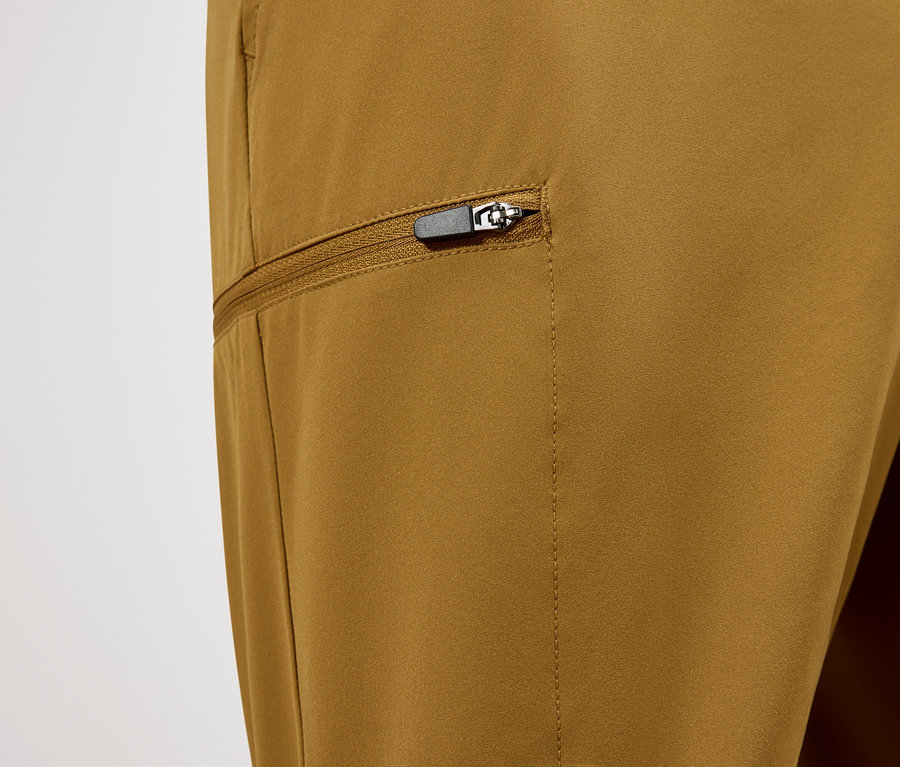 Nahaufnahme einer ockerfarbenen Hose mit einer Reißverschlusstasche.