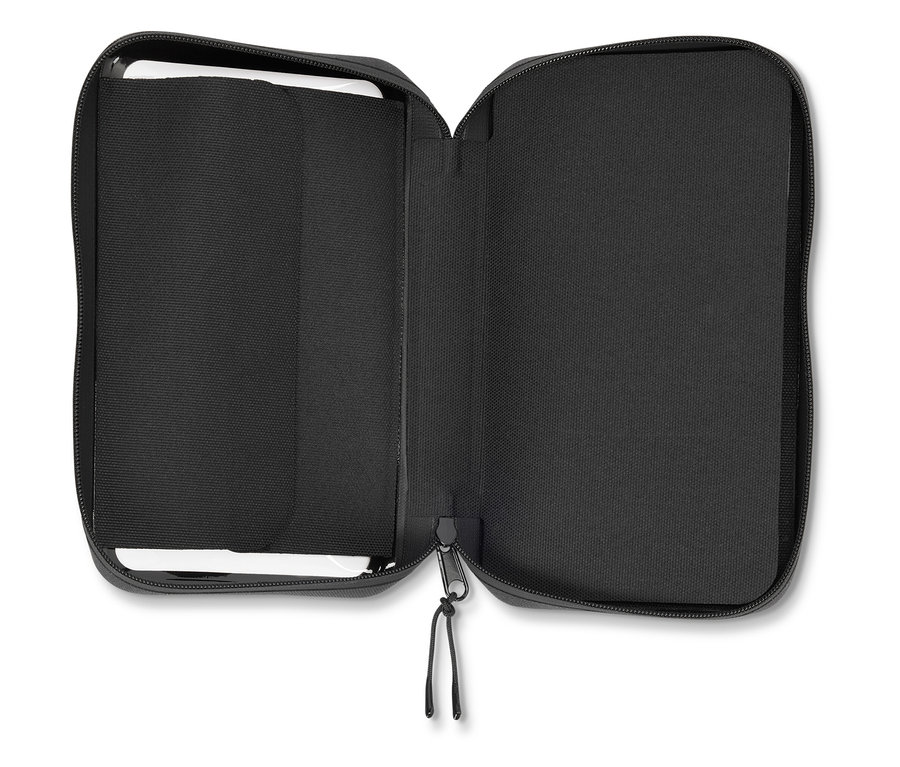 Geöffnete schwarze Reißverschlusstasche, innen gefüttert und mit einer kleinen weißen Tafel.