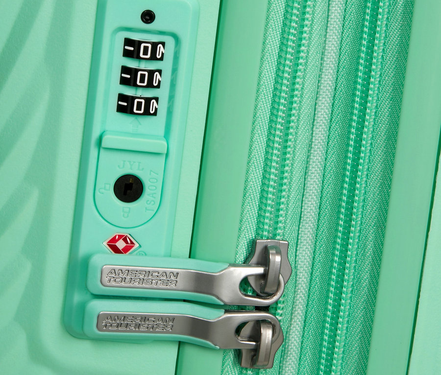 Nahaufnahme eines mintgrünen American Tourister Koffers mit Reißverschluss und Zahlenschloss.
