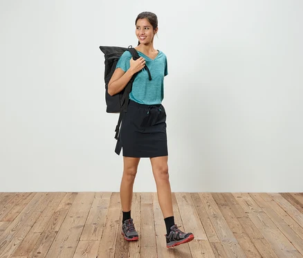 Eine Frau mit einem Rucksack steht auf einem Holzboden.