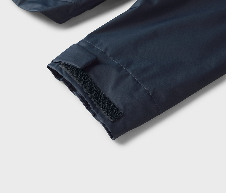 Nahaufnahme eines marineblauen Jackenärmels mit Klettverschluss am Bündchen.