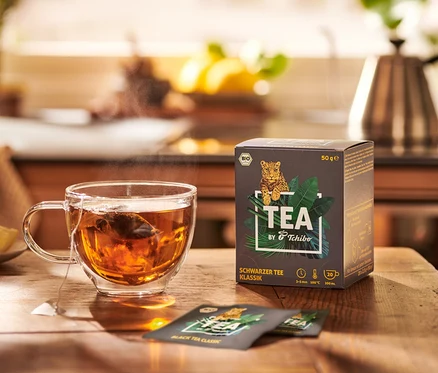 Teetasse neben Packung TEA by Tchibo Bio Schwarzer Tee Klassik.