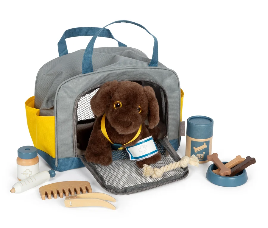 Brauner Plüschhund in grauer small foot Tasche mit blauen Details und gelben Taschen, zusammen mit medizinischem Zubehör.