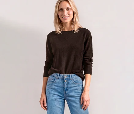 Lächelnde Frau trägt einen braunen Street One Strickpullover und helle Jeans.
