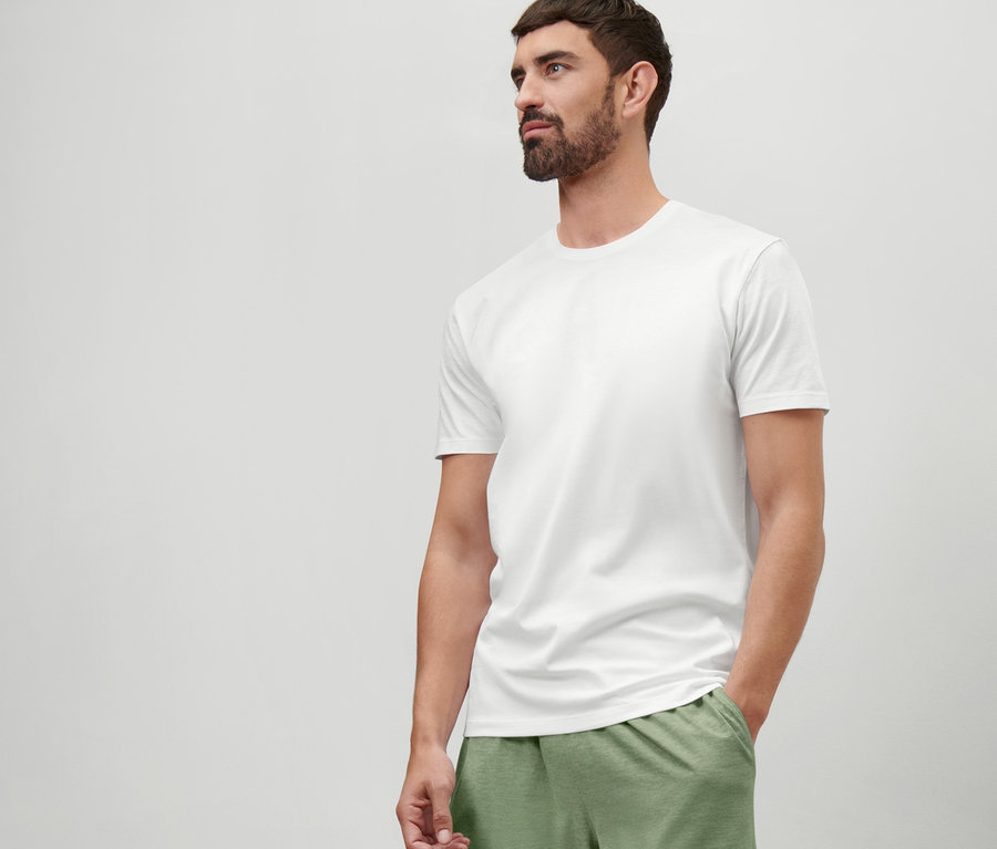 Mann trägt ein weißes T-Shirt mit Rundhalsausschnitt und grüne Shorts.