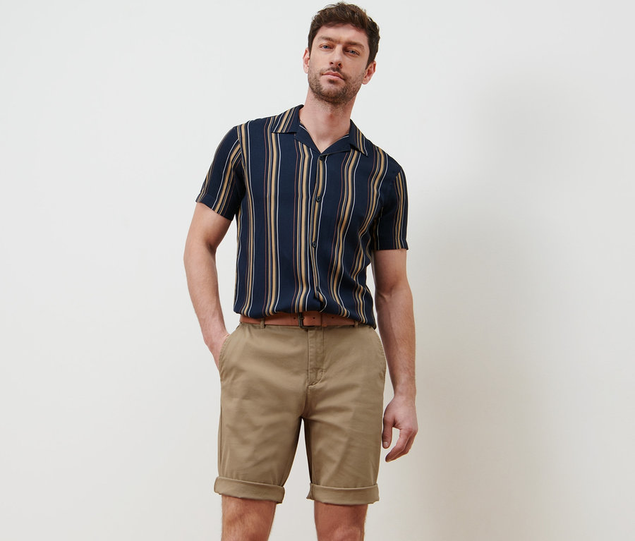 Mann posiert in beigen Chino-Shorts.