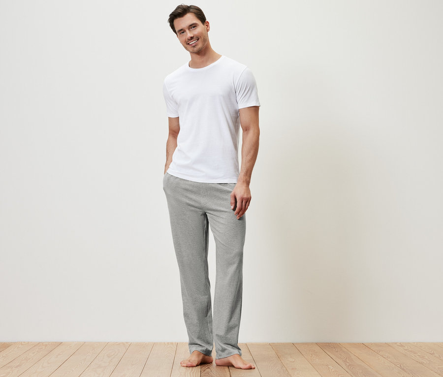 Mann trägt ein weißes T-Shirt und eine graue Relaxhose.