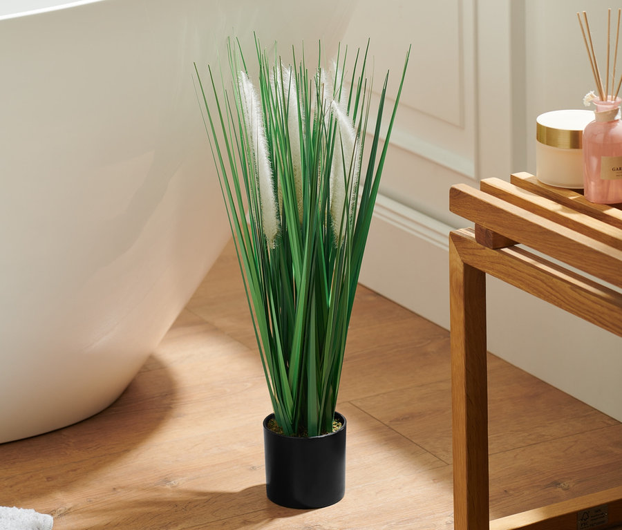 Im Badezimmer steht eine Kunstpflanze »Gräser und Pampas« im Topf neben einer Badewanne.