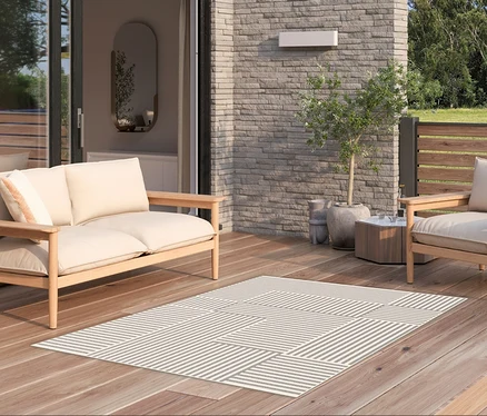 Möblierung auf einer Holzterrasse mit beigem Sofa, Sessel und dem Outdoor-Teppich »Lines«.