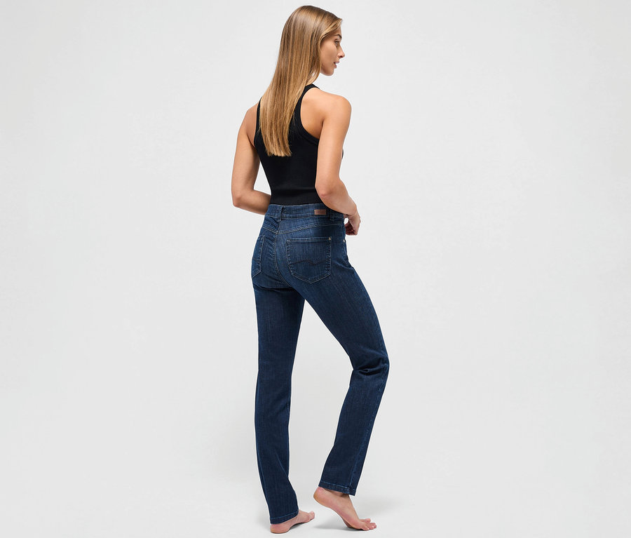 Eine Frau steht mit dem Rücken zum Betrachter und trägt eine dunkelblaue Angels Jeans »Cici« Slim Fit und ein schwarzes Tanktop.