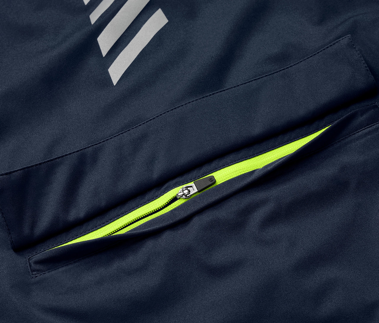 Detail einer blauen Rad-Regenjacke mit neongrünem Reißverschluss an der Tasche und reflektierenden Elementen.