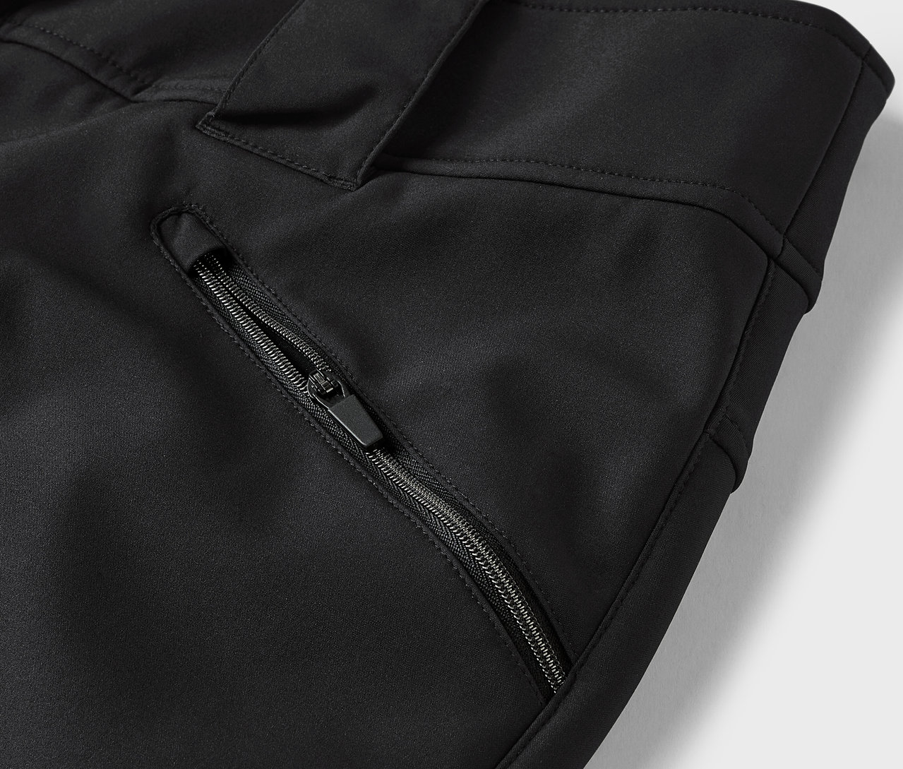 Detail einer schwarzen Hose mit Reißverschlusstasche.