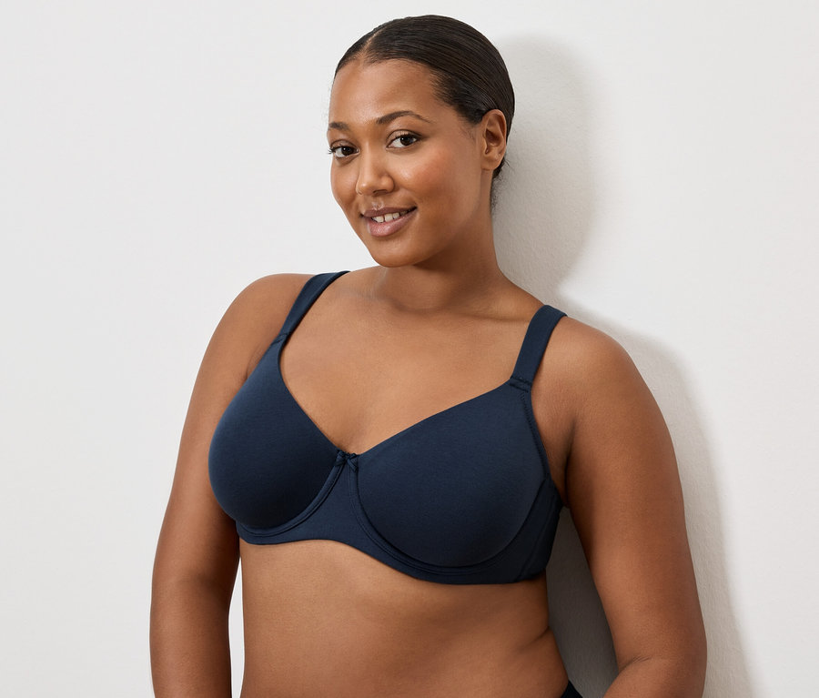 Frau mit dunklem Haar trägt einen dunkelblauen BH.