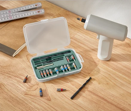 Ein Set für Schraub- und Bohrmaschinen liegt offen neben einem Bohrer auf einem Holztisch.