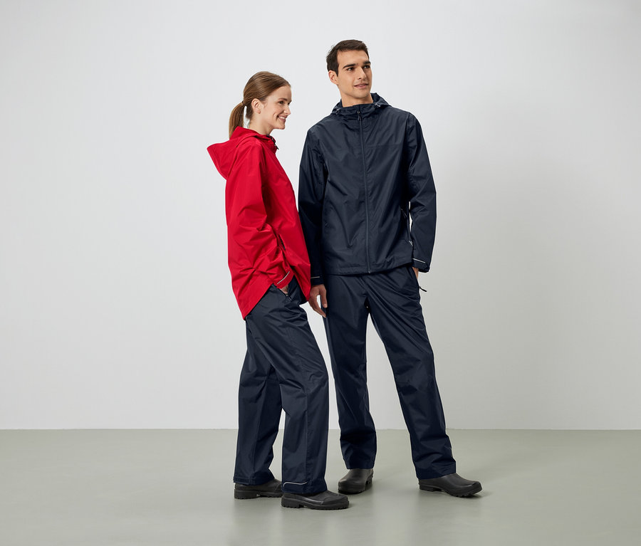 Ein Mann und eine Frau stehen nebeneinander und tragen Regenjacken und Regenhosen.