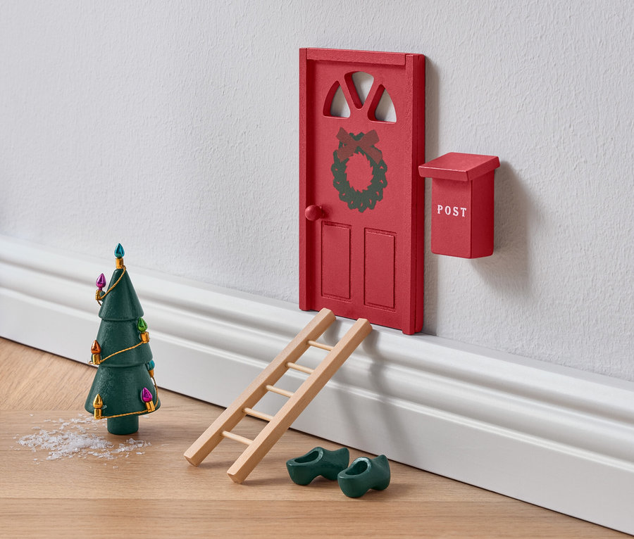 Miniaturrote Tür mit Kranz, Leiter, grünen Holzschuhen und Weihnachtsbaum.