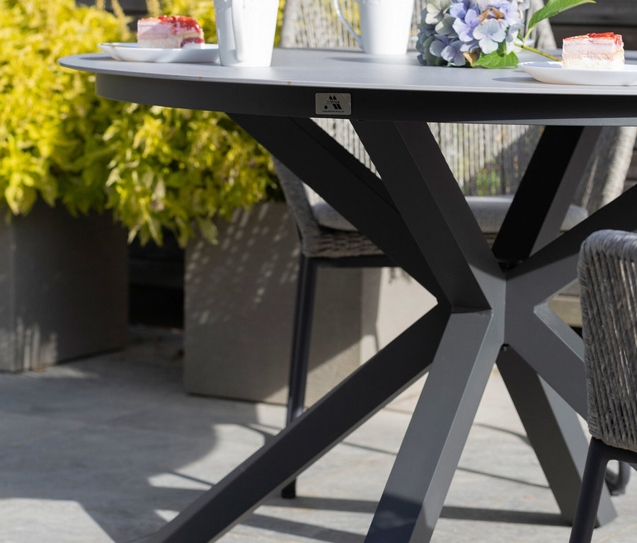 Auf dem deVries Tisch mit einem Durchmesser von ca. 120 cm stehen Tassen, Kuchen und Blumen.