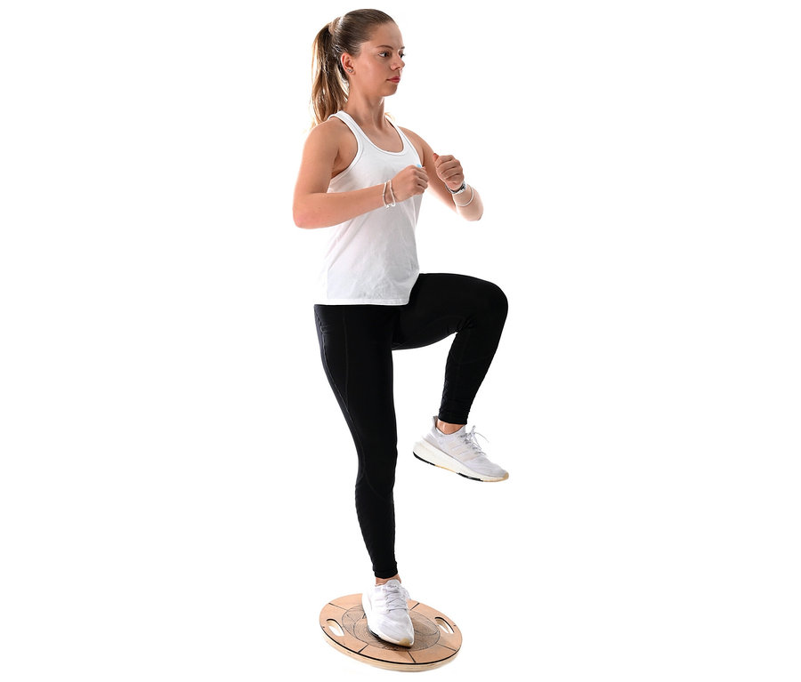 Junge Frau balanciert auf einem F2 Round Balance Plate, das linke Bein angehoben.