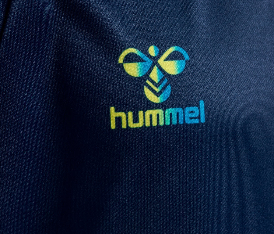 Detailaufnahme eines dunkelblauen Stoffes mit dem Hummel-Logo in Gelb und Türkis.