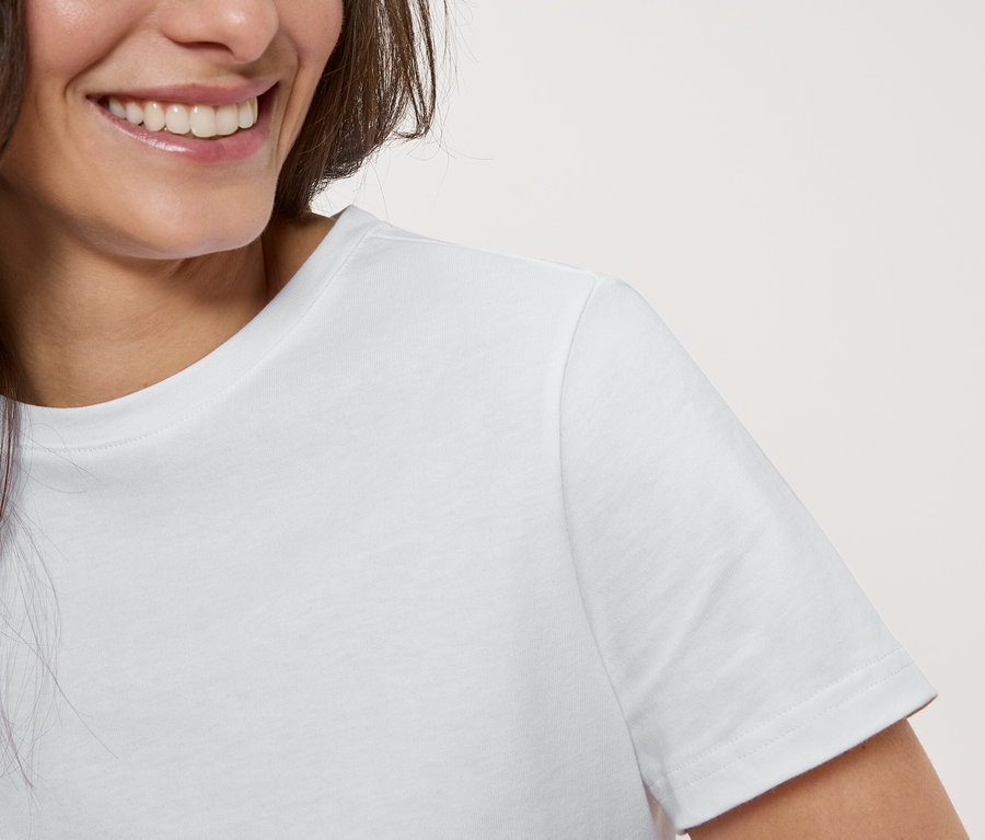 Nahaufnahme einer lächelnden Frau mit weißem T-Shirt.
