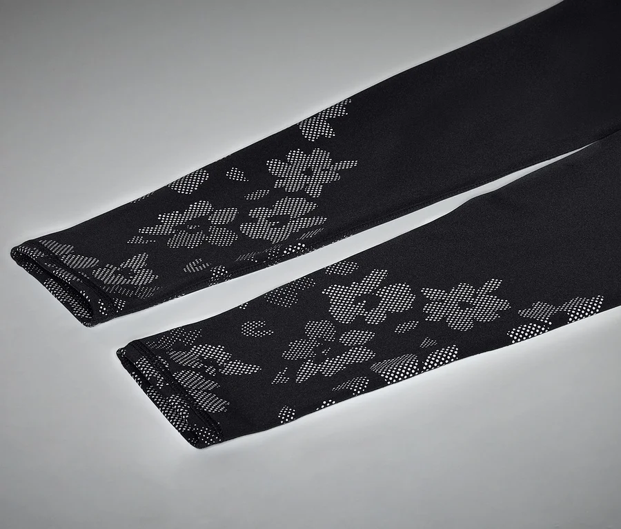Nahaufnahme von zwei schwarzen Leggings mit Blumenmuster auf grauem Hintergrund.