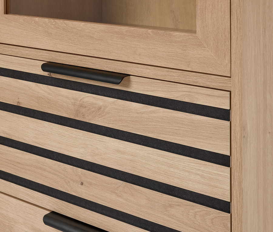 Detailaufnahme eines hellbraunen Holzschranks mit Schubladen, die mit schwarzen horizontalen Akzenten versehen sind und schwarze, horizontale Griffe haben.
