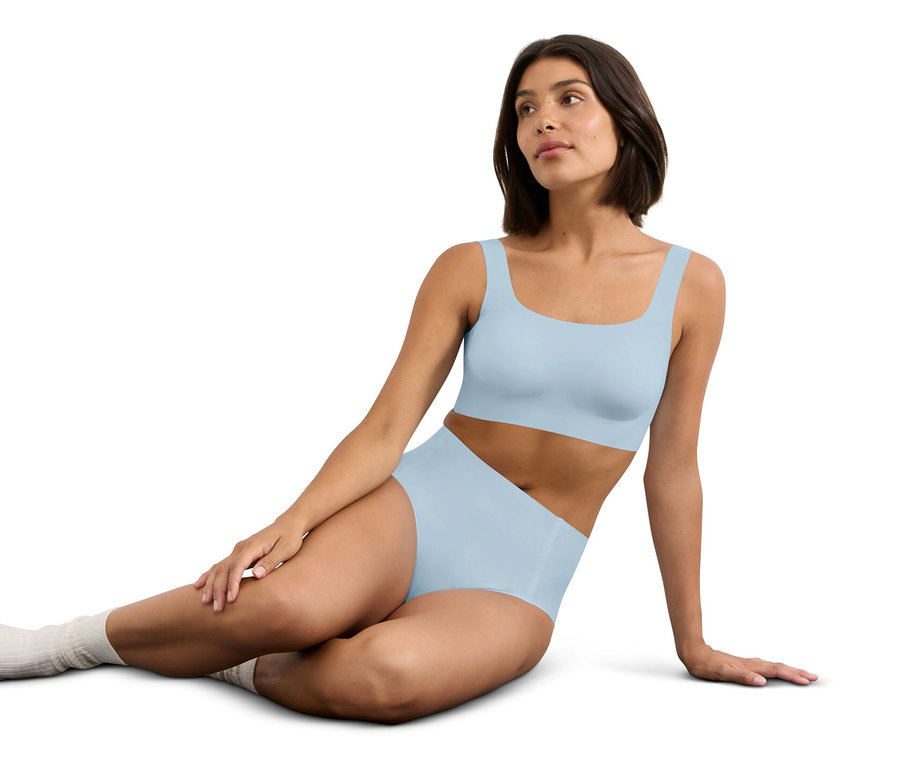 Frau sitzt, trägt hellblaues, trägerloses BH-Top und passende hohe Unterhose.
