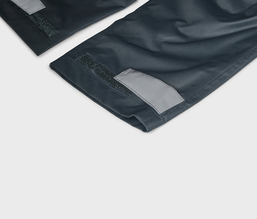 Detailansicht von marineblauen Hosenbeinen mit Klettverschluss und reflektierenden Details an den Säumen.