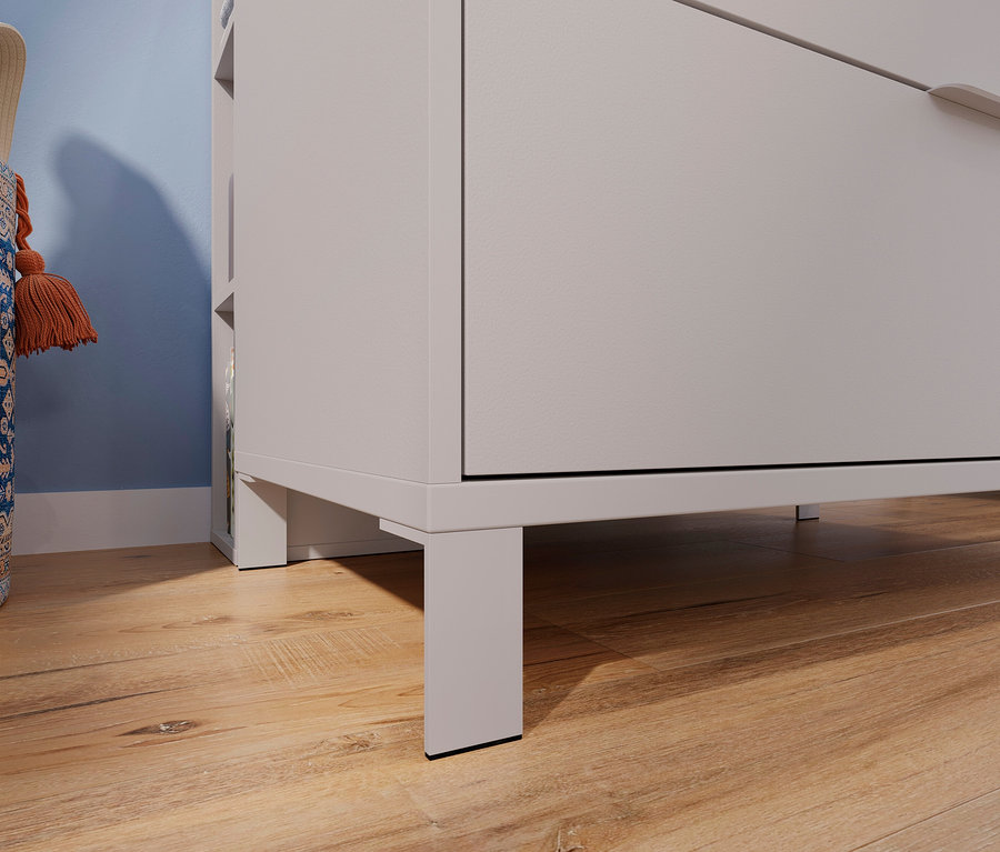 Detailaufnahme einer hellgrauen Kommode auf einem Holzboden, daneben eine blau gemusterte Stofftasche.