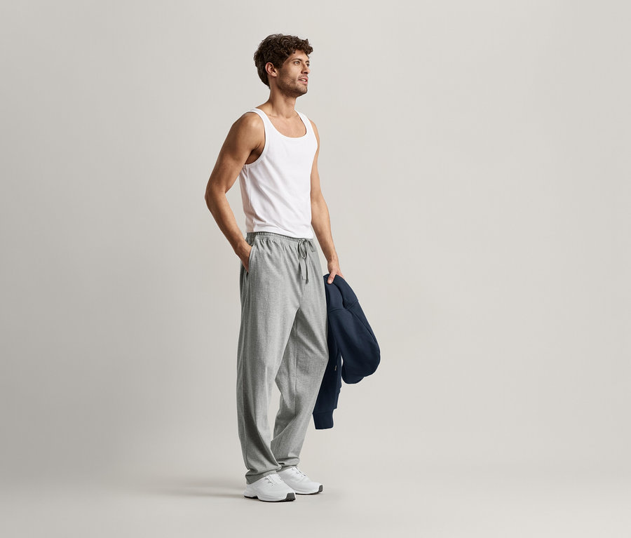 Mann mit weißem Tanktop und grauer Relaxhose.